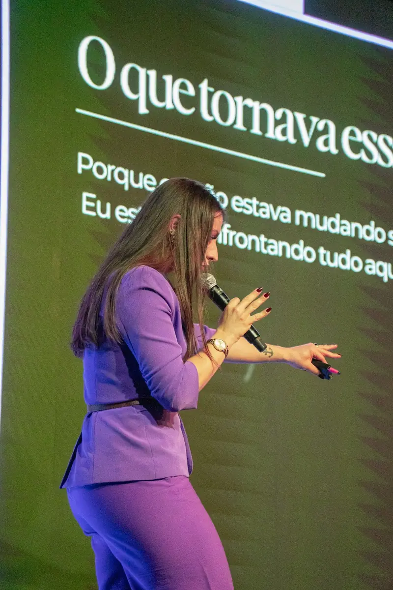 Bell apresentando no palco com slide projetado ao fundo.